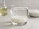 limpiar energías negativas hogar ritual — vaso de vidrio con sal gruesa, vinagre y agua con burbujas
