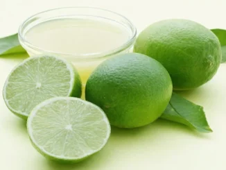 Vaso de agua tibia con rodaja de limón fresco y fondo natural, listo para tomar en ayunas