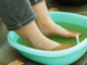 Pies de una persona sumergidos en un recipiente con agua y vinagre (pediluvio), remedio casero para eliminar hongos y el mal olor.