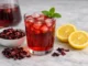 agua de jamaica beneficios receta — vaso rojo con hielo, menta, limón y flor de hibisco seca